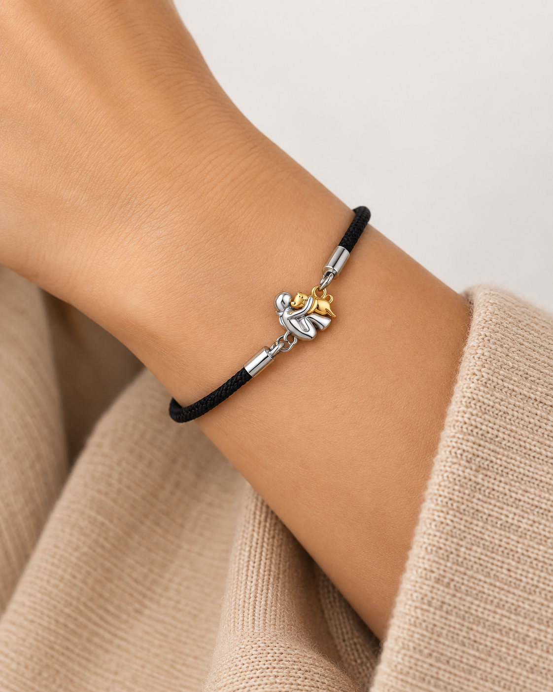 Pulsera de cordón negro con charm bicolor de una figura abrazando a un perro